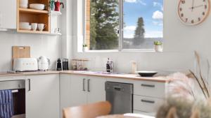 a kitchen with a sink and a window with a clock at Seaview 5 - Great Beach Views in Avoca Beach