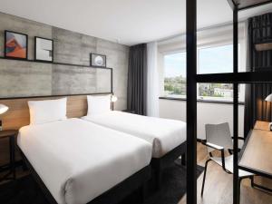 Una habitación de hotel con dos camas y una ventana. en ibis London Earls Court, en Londres
