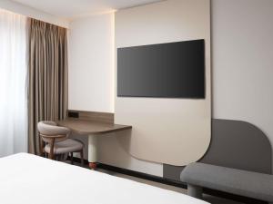 Habitación de hotel con escritorio y TV en la pared en ibis London Earls Court, en Londres 190 fotos más