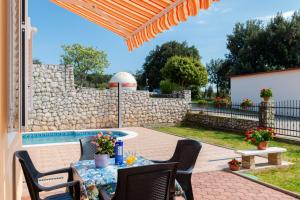 a patio with a table and chairs and a pool at Am Südhang Gelegen Mit Meerblick in Brovnije