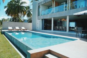 a swimming pool in front of a house at Casa Waua | PÉ NA AREIA, rooftop, borda infinita in Barra do Camaragibe