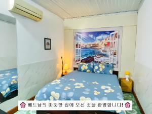 a bedroom with a blue bed with a painting on the wall at Nam Mỹ Vân Homestay - ĐH Công nghiệp Thái Nguyên in Thái Nguyên