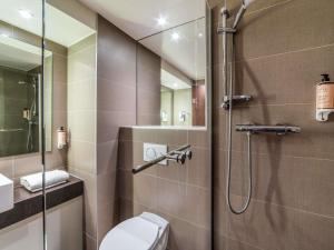 a bathroom with a shower with a toilet and a sink at Mercure Caen Cote De Nacre in Caen