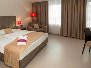 a hotel room with a bed and a chair at Hotel Mercure Graz City in Graz +95 photos