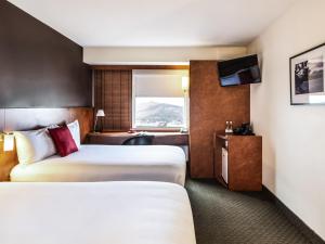 a hotel room with two beds and a television at Ibis Christchurch in Christchurch