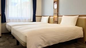 Dos camas en una habitación de hotel con ventana. en Toyoko Inn Tokyo eki Shin ohashi Mae, en Tokio