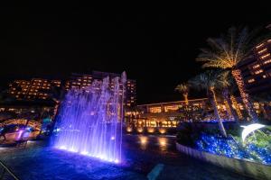 uma fonte de água em frente a uma cidade à noite em Ryukyu Hotel & Resort Nashiro Beach em Itoman