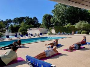 a group of people doing yoga by a swimming pool at Chalet 34m² 6 Pers - Terrasse et Salon de Jardin - API-1-52-708 in Sainte-Eulalie-en-Born
