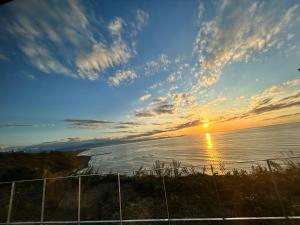 a sunset over the ocean with a fence at the SHIHACHI 