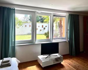 a living room with three windows and a tv at 1,5 Zimmer Ferienwohnung in Luzern