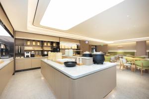 JI Hotel Shanghai Wujiaochang Changhai Hospital في شانغهاي: مطبخ كبير مع طاولة عليها أوعية