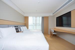 JI Hotel Shanghai Wujiaochang Changhai Hospital في شانغهاي: غرفة فندقية بسريرين وتلفزيون بشاشة مسطحة
