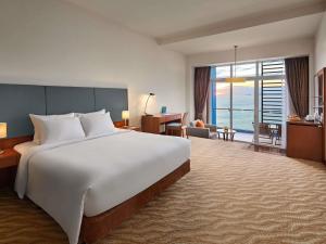a bedroom with a large bed and a living room at Novotel Nha Trang in Nha Trang
