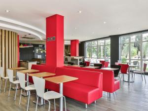 a restaurant with red furniture and tables and windows at ibis Sao Jose dos Campos Colinas in São José dos Campos