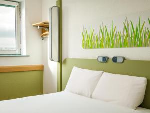 a bedroom with a bed with a plant on the wall at ibis budget Sheffield Arena in Sheffield