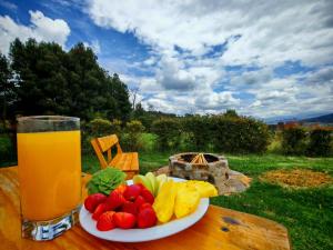 a plate of fruit and a glass of juice on a table at Tacama, acogedoras cabañas cerca a termales in Paipa +27 photos