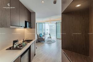 a kitchen with wooden cabinets and a living room at Panorama Win Residences Nha Trang in Nha Trang