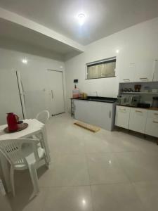 a large white kitchen with a table and a refrigerator at Casa do Pepe em Barra de Jacuípe in Camaçari