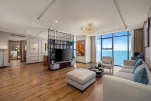 a living room with a couch and a tv at Peninsula Hotel Danang in Da Nang