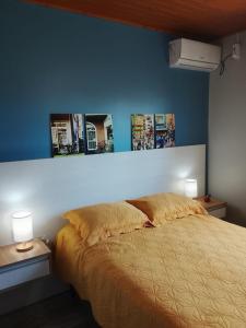 ein Schlafzimmer mit einem Bett mit zwei Lampen und Bildern an der Wand in der Unterkunft A Casa Amarela - Morada dos Maçaricos - Tranquilidade próxima ao mar in Balneário Gaivotas