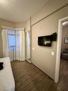 ein Schlafzimmer mit einem Bett und einem Fernseher an der Wand in der Unterkunft 1155 golden 55m2 1 quarto frente mar avenida beira mar in Fortaleza