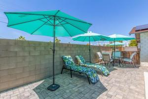 Un patio con dos sillas y una sombrilla verde. en Pristine Sunset- In Old Town - Private Pool - BBQ, en Scottsdale