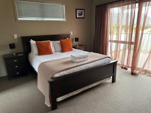 a bedroom with a large bed with orange pillows at Sunny Bob Lee Place in Wanaka