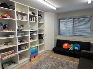 a living room with a black couch and book shelves at Sunny Bob Lee Place in Wanaka