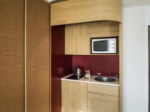 a small kitchen with a sink and a microwave at Aparthotel Adagio Nantes Centre in Nantes