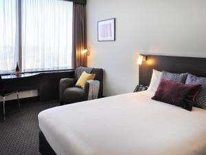 a hotel room with a bed and a chair at ibis Melbourne - Glen Waverley in Glen Waverley +64 photos