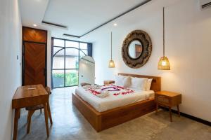 a bedroom with a bed and a table and a mirror at Chopik Villa in Dalung