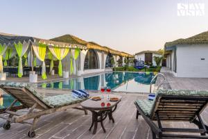 a patio with a table and chairs next to a pool at StayVista at Rissaca Crown with Bonfire in Jaipur