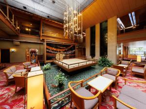a lobby of a hotel with a couch and tables and chairs at Hamanoyu in Suwa