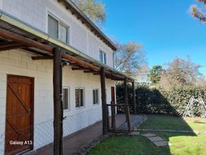 a house with a wooden door next to a yard at Cabañas El Nogal in Villa Anizacate +14 photos