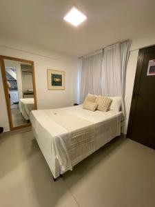 a bedroom with a large white bed with a window at Apartamento à beira-mar em São Miguel do Gostoso in São Miguel do Gostoso