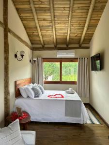 Un dormitorio con una cama grande y una ventana en Pousada Pequeno Oásis Tiradentes, en Tiradentes