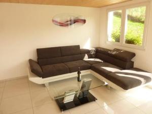 a living room with a brown couch and a glass table at Oberwilen in Vitznau +8 photos