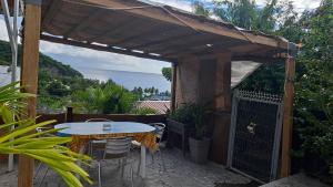 un patio con mesa y sillas bajo una pérgola en Evasion Nord Caraïbe vue mer -plage 5 mn à pieds, en Le Carbet