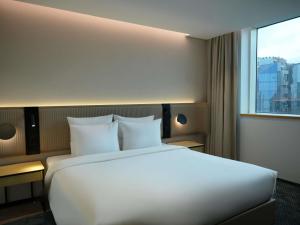 a large white bed in a hotel room with a window at Novotel Riyadh Al Anoud in Riyadh