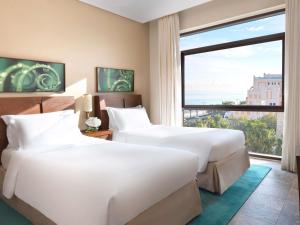 deux lits dans une chambre d'hôtel avec une grande fenêtre dans l'établissement Sofitel Dubai The Palm Resort & Spa, à Dubaï 102 autres photos