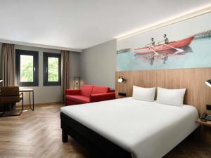 a hotel room with a bed and a red chair at Ibis Budapest Heroes Square in Budapest