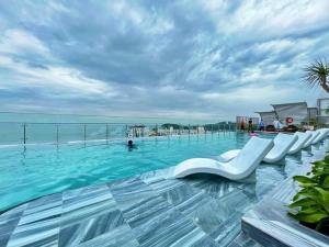 una piscina con sillas blancas en el agua en The Sóng Apartment Vũng Tàu, en Vung Tau