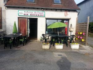 a restaurant with tables and chairs and a green umbrella at Chalets avec grande terrasse et jeux enfants près de Montluçon - FR-1-489-402 in Mesples