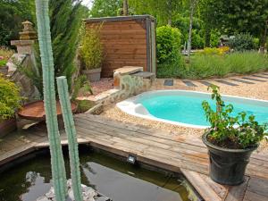 Una bañera de hidromasaje en un jardín con terraza de madera. en Loft Privatisé de Charme avec Piscine et Jardin Provençal - FR-1-489-337, en Cognat-Lyonne