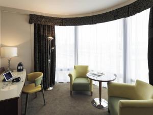 a hotel room with chairs and a table and a window at Mercure Sheffield St Paul's Hotel & Spa in Sheffield