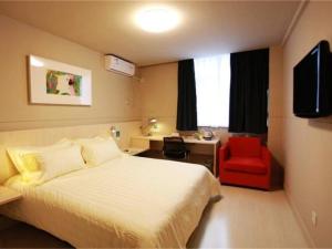 une chambre d'hôtel avec un lit et un fauteuil rouge dans l'établissement Jinjiang Inn Jiaozuo Jianshe Road, à Jiaozuo