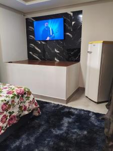 a room with a tv and a bed and a refrigerator at Lar Doce Lar Realizando Sono!!! in Arcos