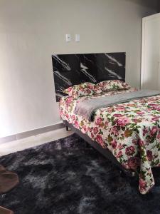 a bedroom with a bed with a floral comforter at Lar Doce Lar Realizando Sono!!! in Arcos