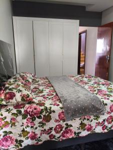 a bedroom with a bed with a floral bedspread at Lar Doce Lar Realizando Sono!!! in Arcos +2 photos