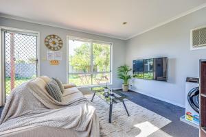 a living room with a couch and a clock on the wall at StayAU 4BR Family-Friendly Home near Deakin Uni in Whittington